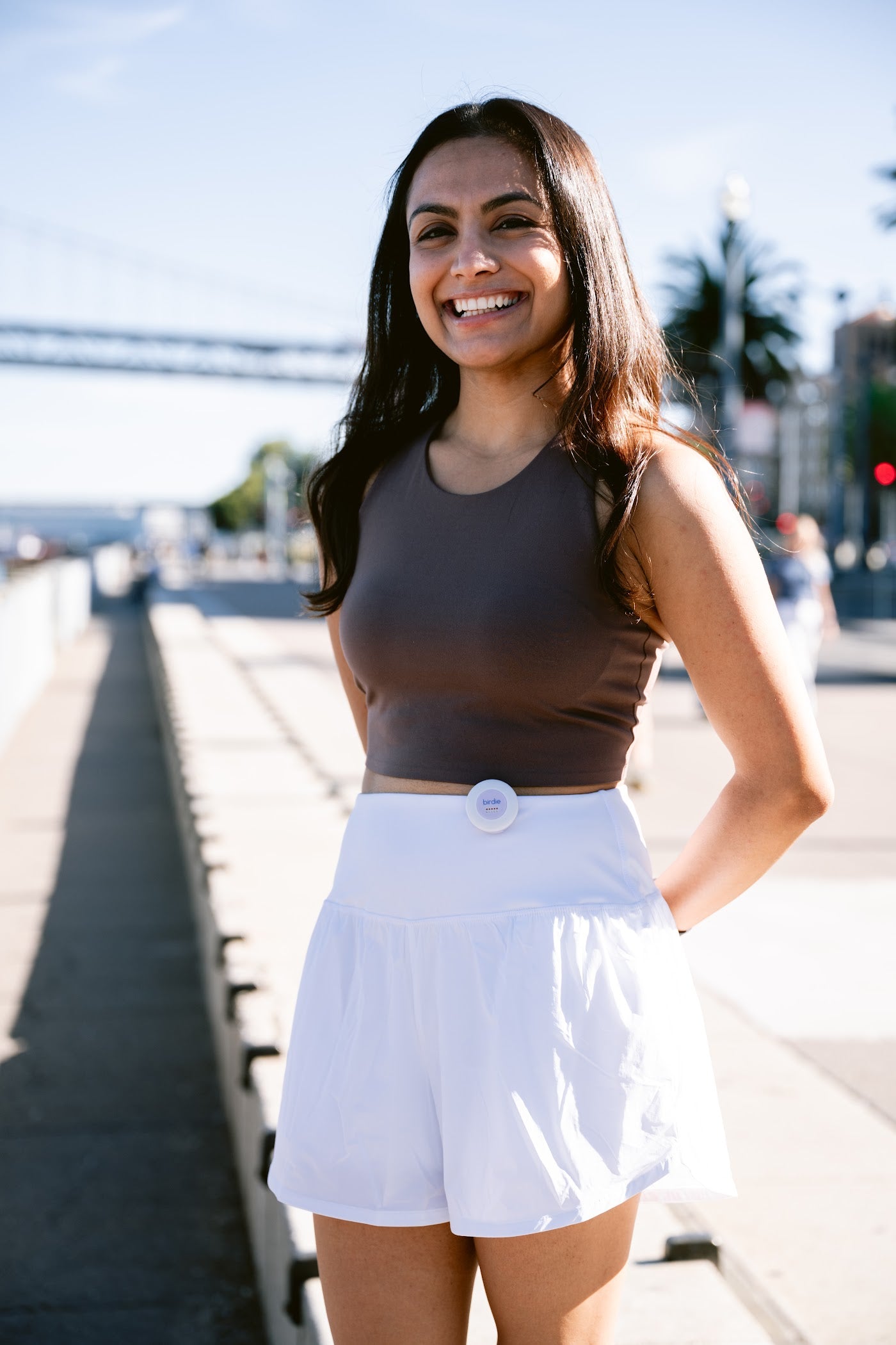 Woman walking with the Birdie Disc clipped to her waistband, hands free