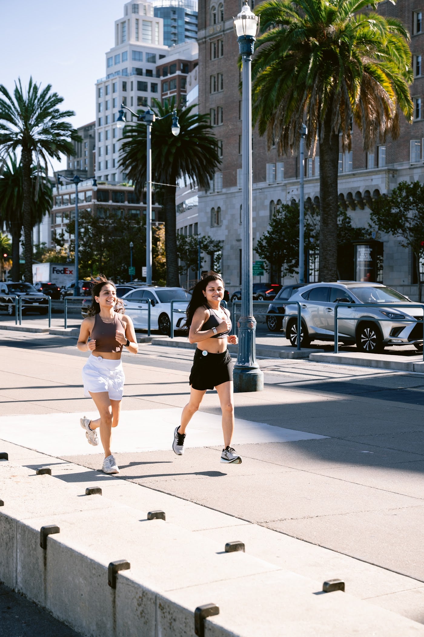 Two women running together, each carrying a Birdie Disc