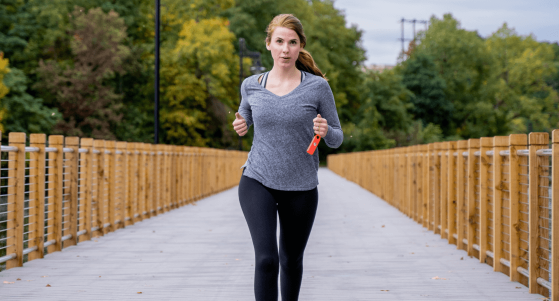 A woman jogging on a wooden bridge surrounded by greenery.