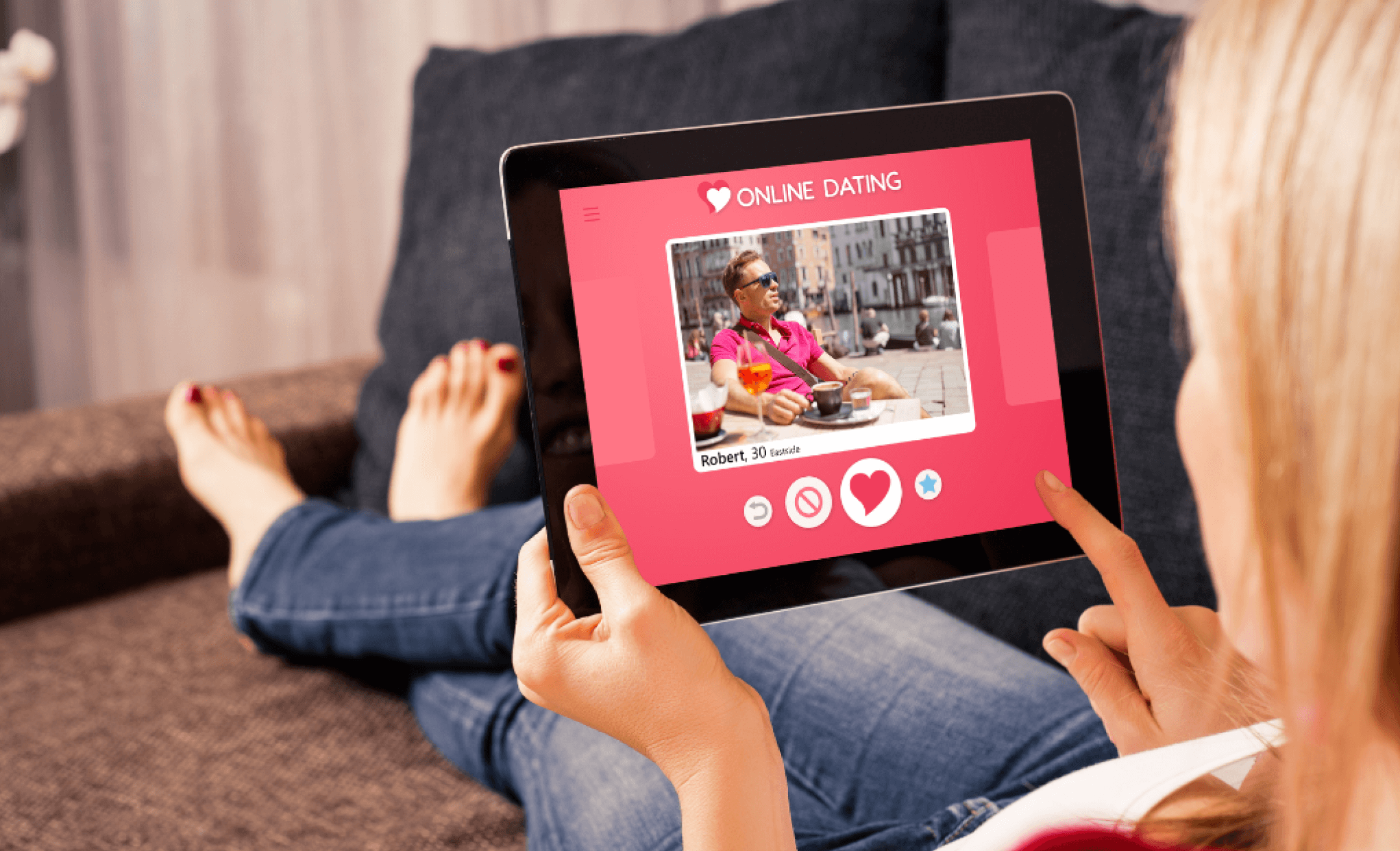 Person using a tablet viewing a male profile on an online dating app.