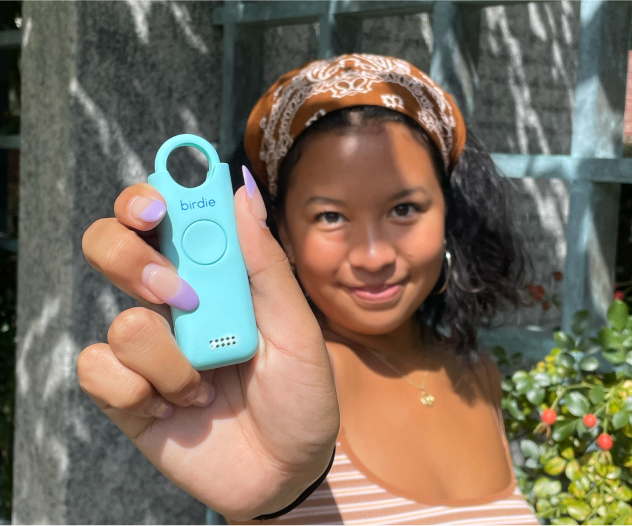 Woman holding a blue safety device called 'birdie' with a smile.